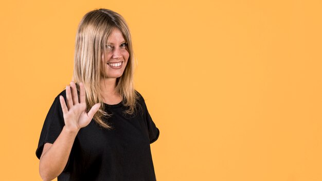 Smiling young woman standing over yellow backdrop