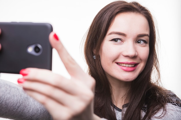 Улыбается молодая женщина с автопортрет с мобильного телефона