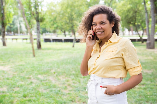 Smiling young woman talking on phone in city park