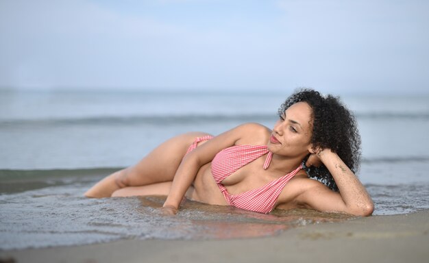 Улыбающаяся молодая женщина в купальнике на пляже