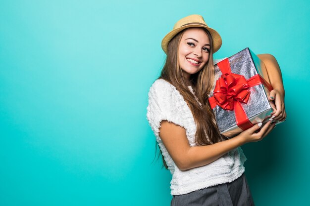 ギフトリボンと赤いプレゼントボックスを保持している白いTシャツと帽子の若い女性の笑顔