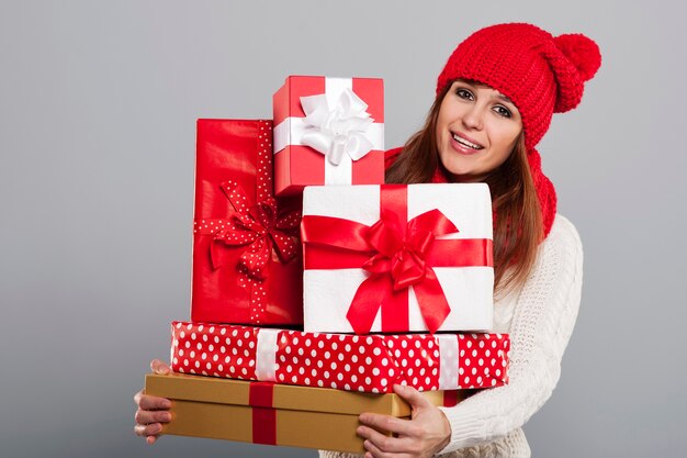 크리스마스 선물을 많이 들고 겨울 모자에 웃는 젊은 여자