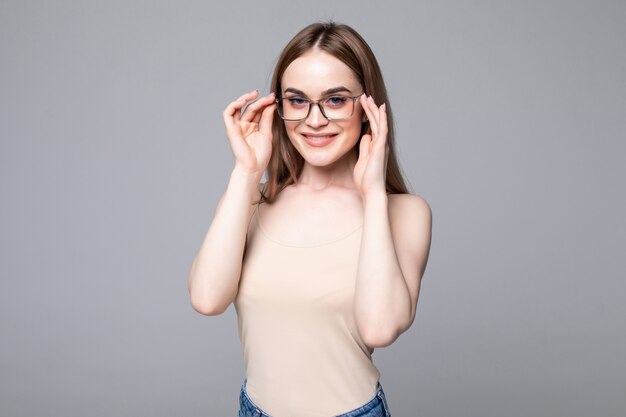 Smiling young woman with eyeglasses over gray wall