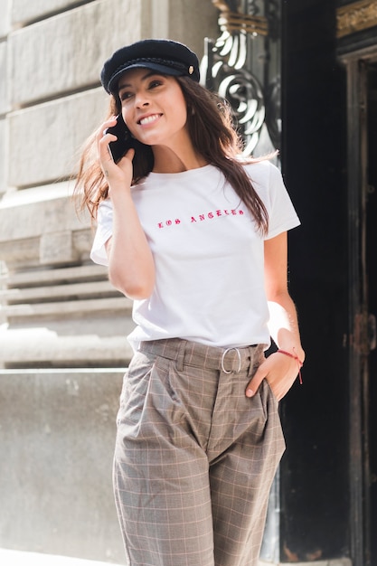 Free photo smiling young woman with hand in her pocket talking on mobile phone