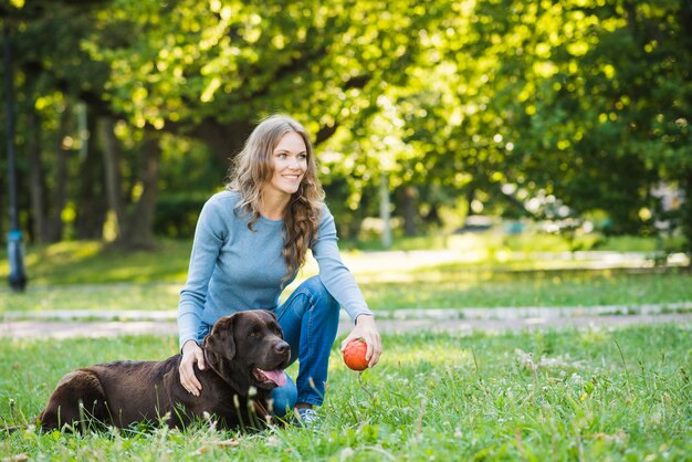 庭で彼女の犬と笑顔の若い女性
