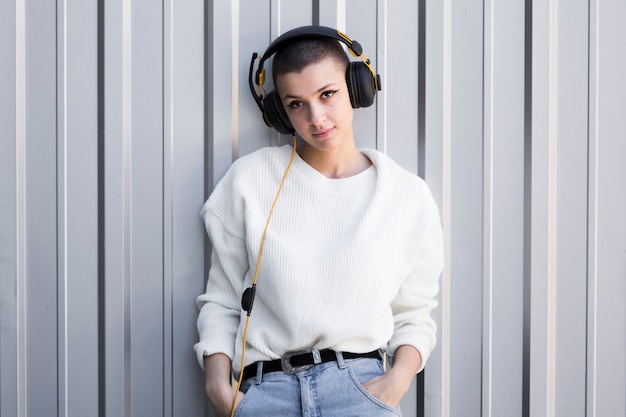 Smiling young woman with shaved head and headphones 