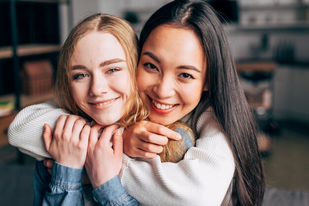 Smiling young women embracing at home