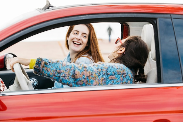 Foto gratuita giovani donne sorridenti che si siedono in automobile