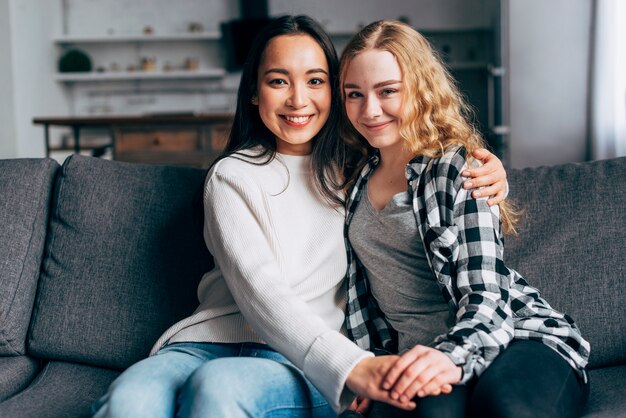 Smiling young women sitting on couch together