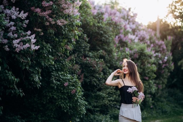 Free photo the smilling girl stands near bushes with flowers