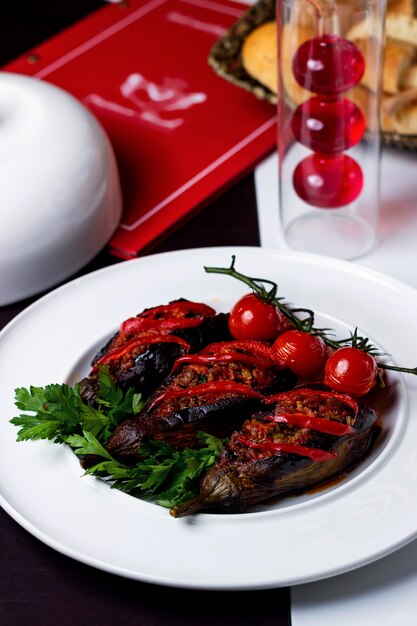 Smoked aubergine with minced meat garnished with cherry tomato and parsley