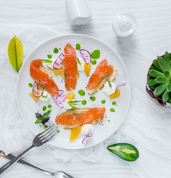 Smoked salmon fillet with green sauce inside white plate.