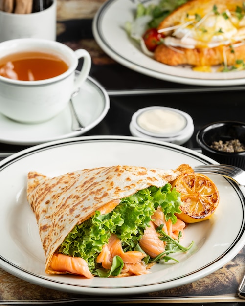 Smoked salmon wrap with lettuce, arugula served with grilled lemon