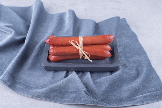 Smoked sausages tied with rope on dark board. 