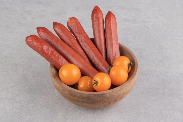 Foto gratuita salsicce affumicate e pomodori in ciotola di legno.
