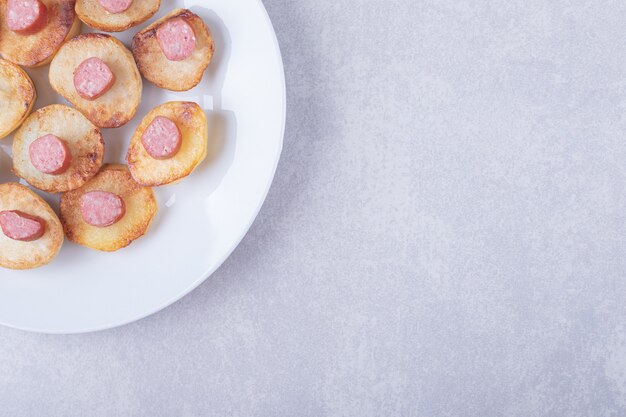 Smoked sausages with fried potato on white plate. 