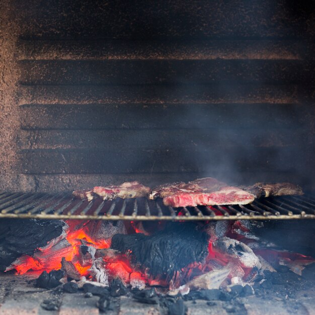 Smoky grilled meat on baked metal sheet in the barbecue