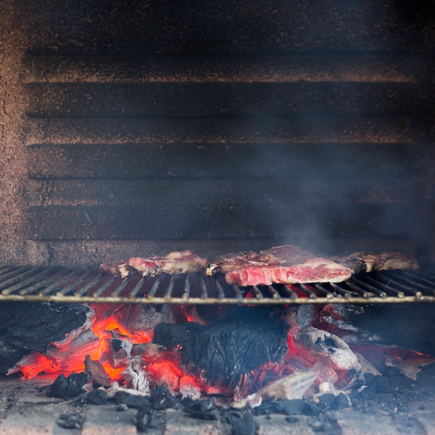バーベキューで焼かれた金属板の上のスモーキーグリル肉