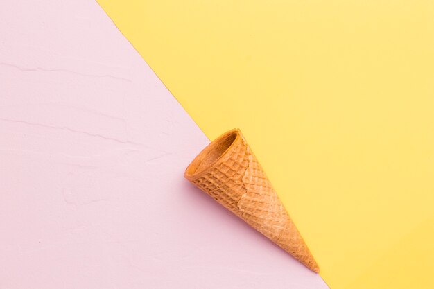 Smooth empty ice cream cone on multicolored surface