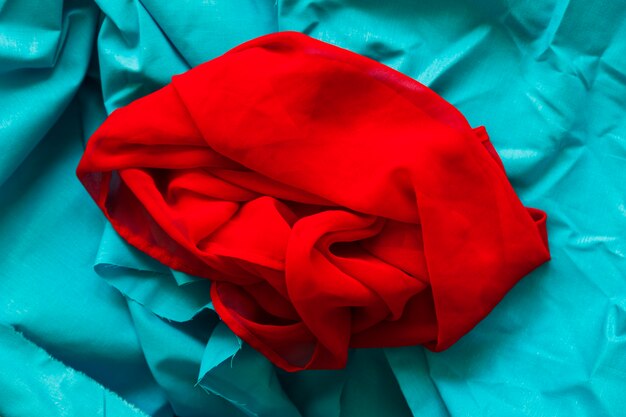 ターコイズ布の背景に滑らかな赤い織物