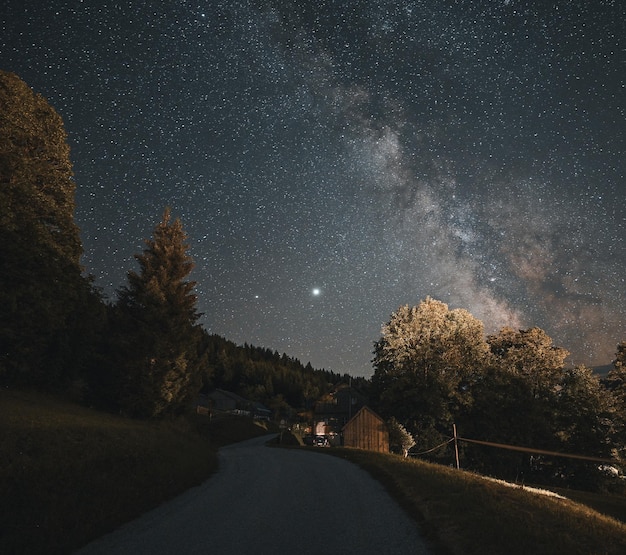 은하수와 함께 밤하늘의 별이 빛나는 하늘 아래 아름다운 시골을 통과하는 부드러운 도로