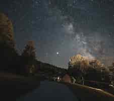 無料写真 天の川のある夜の星空の下、風光明媚な田園地帯を通る滑らかな道