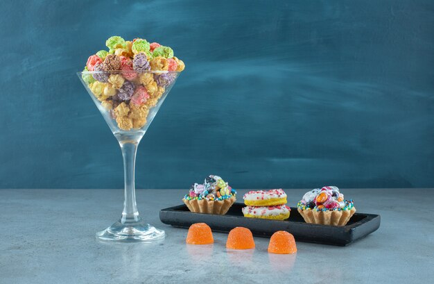 Snack assortment with donuts, popcorns, cupcakes and jelly candies on marble surface