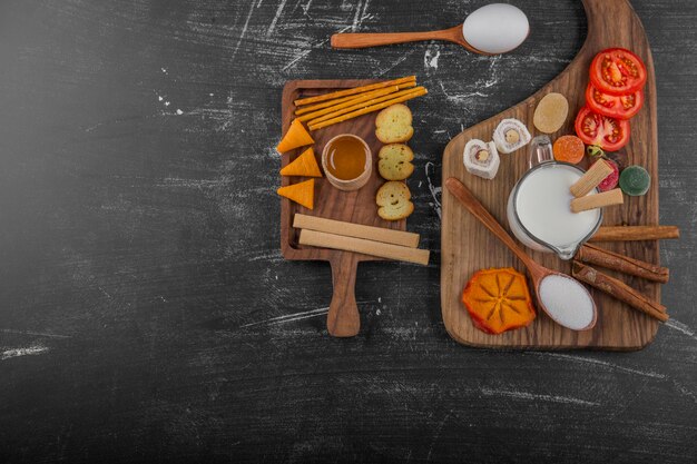 Snack board with crackers and vegetables isolated on black background