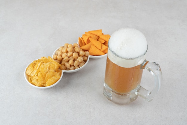 Snack bowls and glass of beer on stone surface