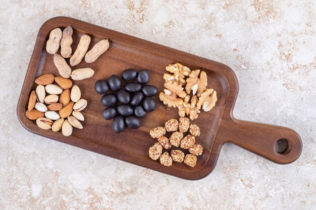 Snack serving with small piles of nuts and candy on a board 