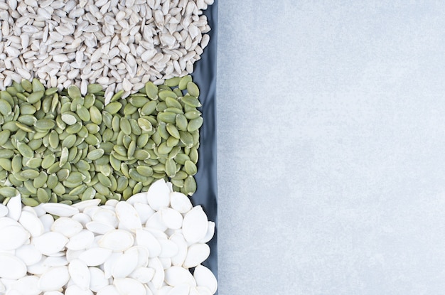 Free photo snack servings of various seeds on a platter on marble surface