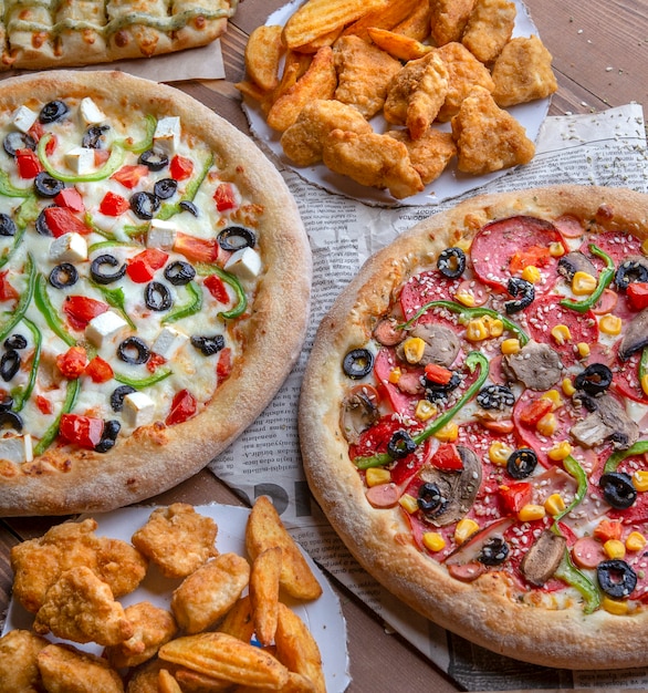 Snack table with pizzas, chicken bbq and fried potatoes