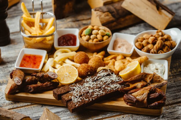 Snacks platter with smoked wings sausages french fries nuts and sauces