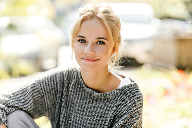 Snapshot of curly blond girl with slight smile looking at camera on street