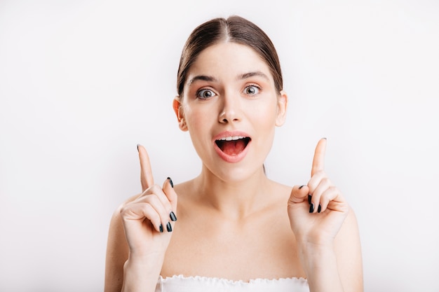 Snapshot of girl without makeup on white wall. Brunette with green eyes has cool idea.