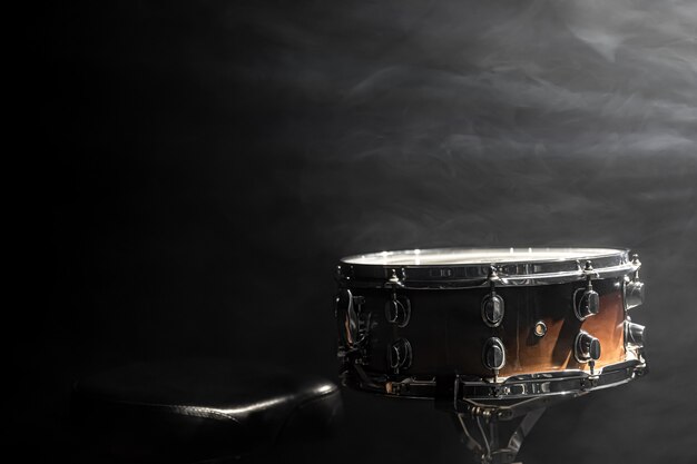 Snare drum on black background, percussion instrument in the dark with stage smoke, copy space.