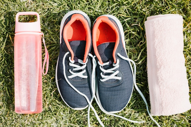 Foto gratuita scarpe da ginnastica tra asciugamano e bottiglia