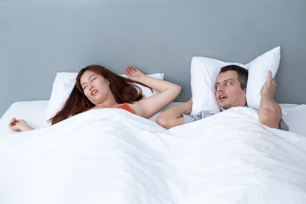 Snoring Woman and Husband Covering Ears