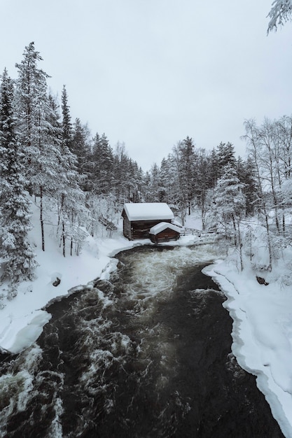 Snow-covered hut by river in the Oulanka National Park, Finland