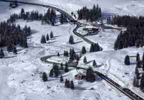 Foto gratuita montagna innevata con strada e alberi