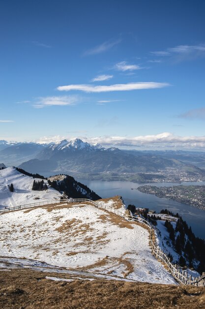 青い空の下でリギ山とスイスの湖のパノラマの景色を望む雪に覆われたビューデッキ