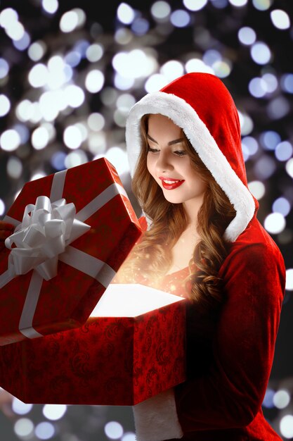 Снегурочка в красном костюме открывает красный подарок на Рождество и Новый год 2018,2019