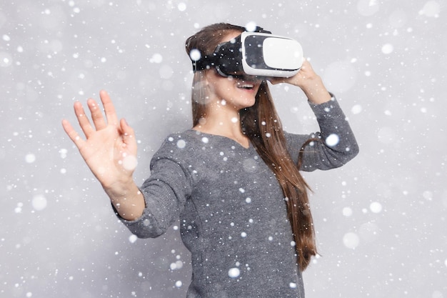 눈, 겨울, 크리스마스, 기술, 가상 현실, 엔터테인먼트 및 사람 개념 - 행복한 여성 가상 현실 헤드셋 또는 3d 안경. 눈 배경 위에 가상 현실 고글을 가진 여자