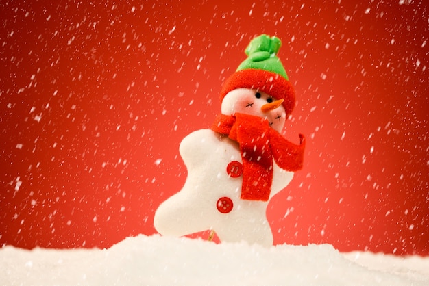Снеговик на снегу с красным фоном