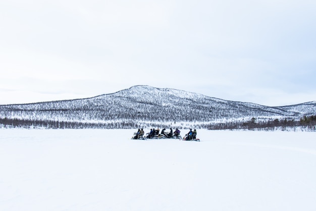 スウェーデン北部の遠くでスノーモービルに乗る人々との雪の日