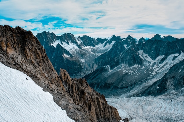 Snowy hill with snow-covered mountains under a cloudy sky