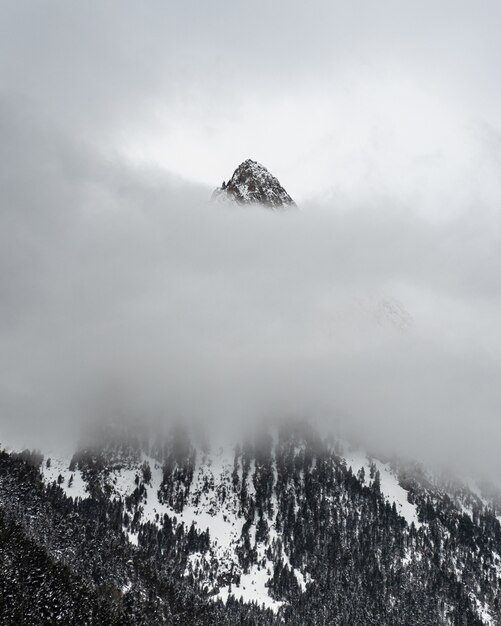 snowy mountain behind layer of clouds