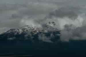 Free photo snowy peaks of the mountains covered by the dark cloudy sky