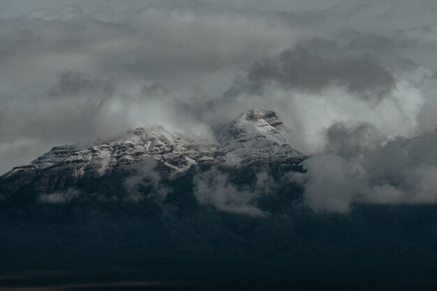 Snowy peaks of the mountains covered by the dark cloudy sky