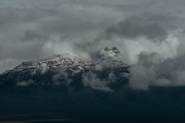 Snowy peaks of the mountains covered by the dark cloudy sky